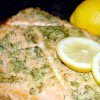 Baked salmon fillet topped with herbs, by Owl Creek Farm, garnished with lemon slices in the background.