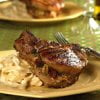 Grilled stuffed pork chop by Owl Creek Farm served with a side of creamy pasta on a yellow plate.