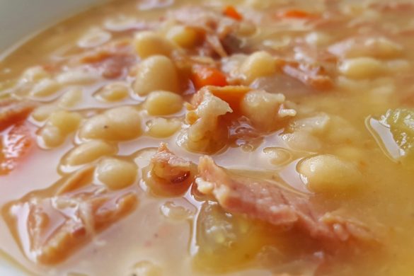 A close-up of a bowl of hearty bean soup with chunks of ham and vegetables, crafted with care by Owl Creek Farm.