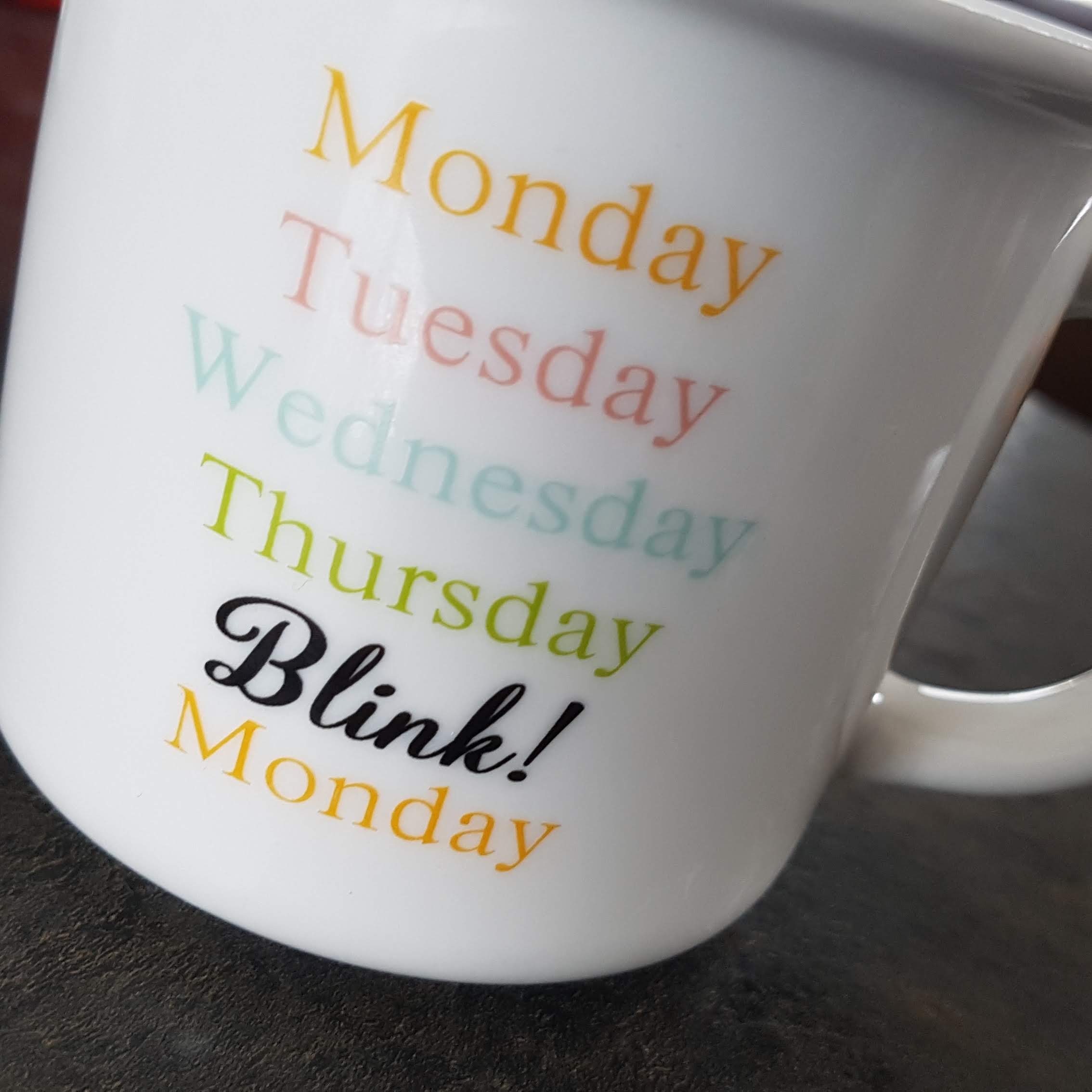 White mug by Owl Creek Farm featuring days of the week: Monday, Tuesday, Wednesday, Thursday, Blink!, and Monday again in vibrant text.